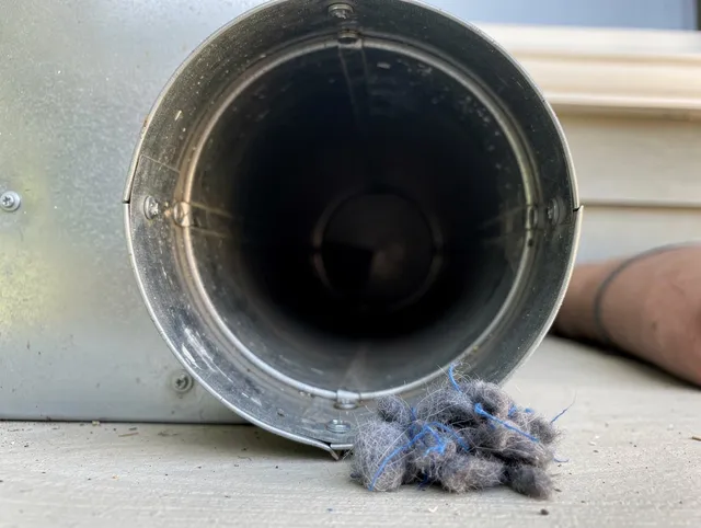 Orange Dryer Vent Cleaning technician using specialized equipment to clear severe dryer vent blockage in Orange